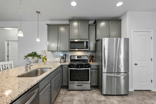 kitchen featuring pendant lighting, gray cabinetry, sink, decorative backsplash, and appliances with stainless steel finishes