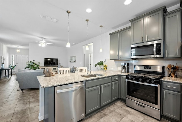 kitchen with sink, decorative backsplash, appliances with stainless steel finishes, decorative light fixtures, and kitchen peninsula