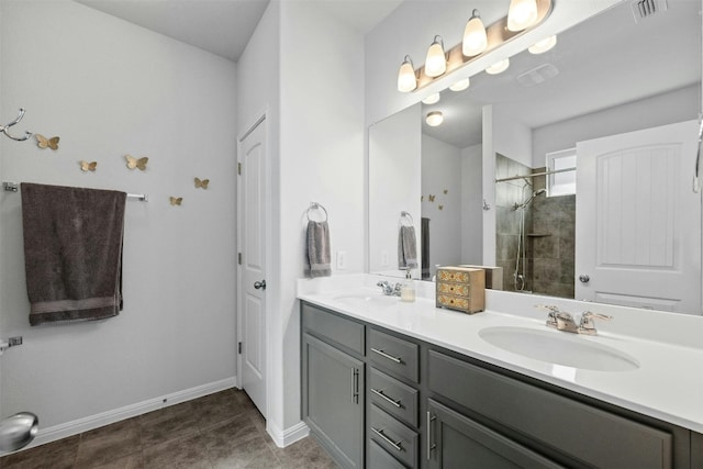 bathroom with a tile shower, vanity, and tile patterned floors