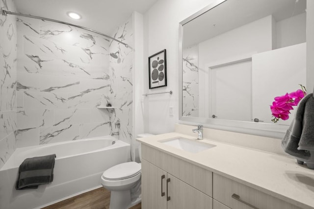 full bathroom featuring hardwood / wood-style floors, vanity, tiled shower / bath combo, and toilet