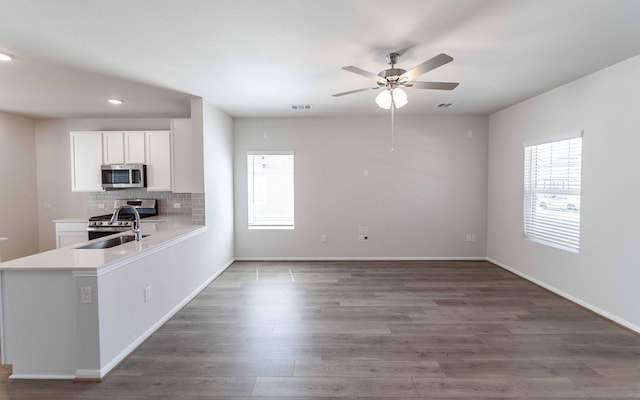 kitchen with tasteful backsplash, ceiling fan, appliances with stainless steel finishes, white cabinetry, and dark wood-type flooring