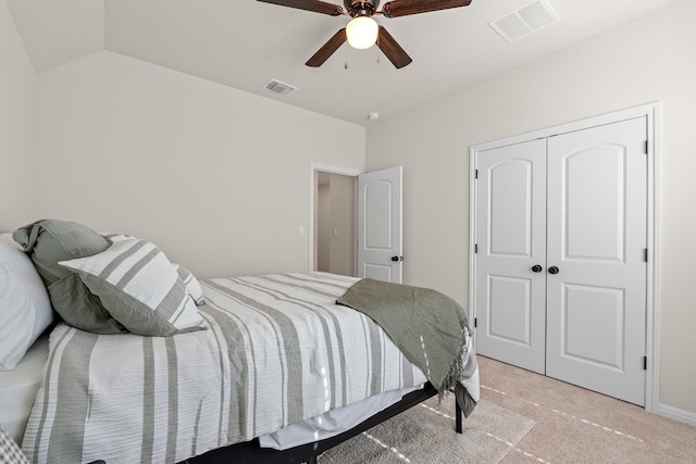 bedroom with ceiling fan, lofted ceiling, light carpet, and a closet