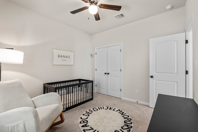 carpeted bedroom with ceiling fan, a closet, and a nursery area