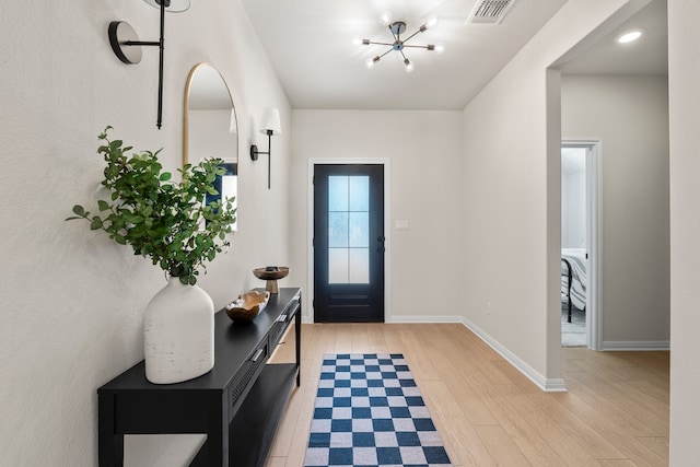 foyer entrance with light hardwood / wood-style flooring and a chandelier