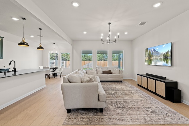 living room featuring sink, light hardwood / wood-style floors, and an inviting chandelier