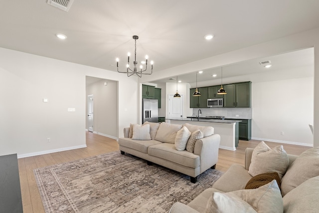 living room with a chandelier, light hardwood / wood-style flooring, and sink