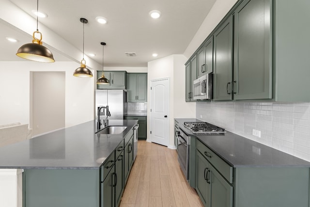 kitchen featuring sink, stainless steel appliances, tasteful backsplash, an island with sink, and decorative light fixtures