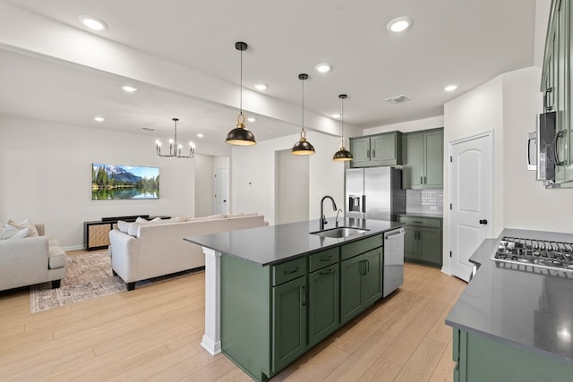 kitchen with pendant lighting, sink, green cabinetry, an island with sink, and stainless steel appliances