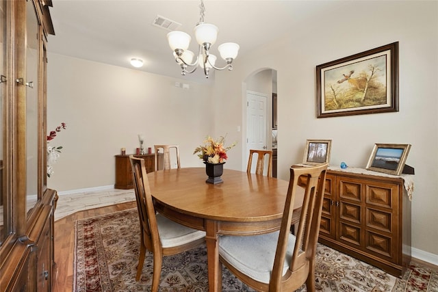 dining room with hardwood / wood-style floors and an inviting chandelier