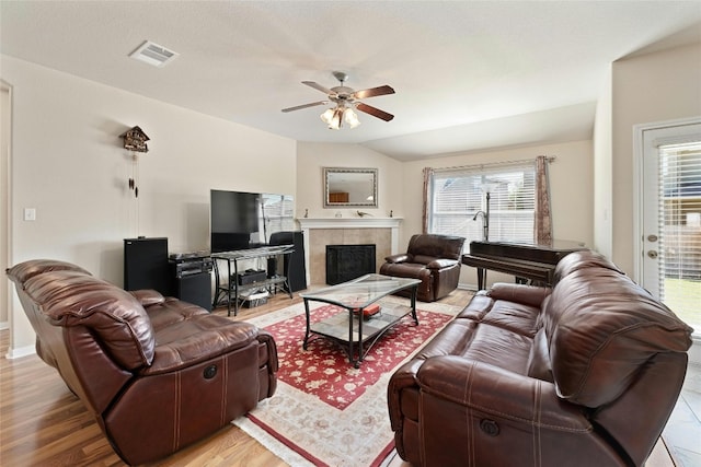 living room with light hardwood / wood-style floors, ceiling fan, a fireplace, and vaulted ceiling