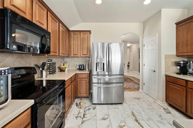 kitchen with lofted ceiling, black appliances, and decorative backsplash