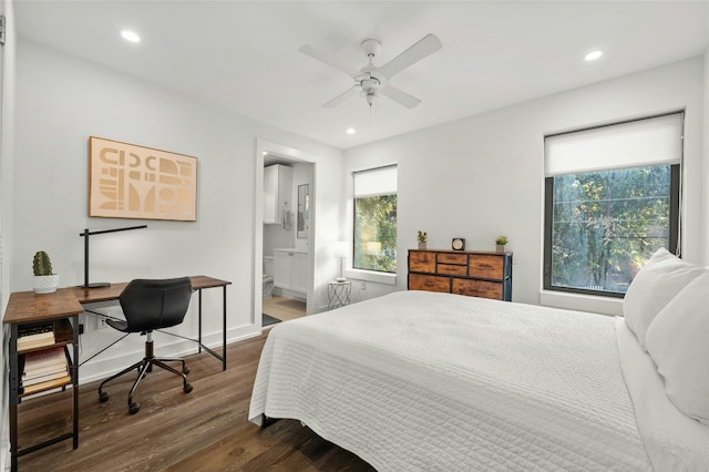 bedroom with ceiling fan, ensuite bath, and dark hardwood / wood-style floors