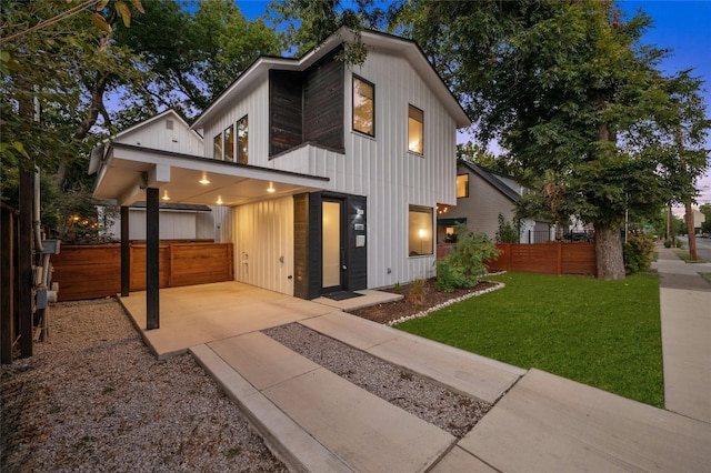 rear view of property with board and batten siding, concrete driveway, and a carport