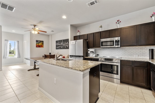 kitchen featuring appliances with stainless steel finishes, a kitchen island with sink, sink, and light stone counters