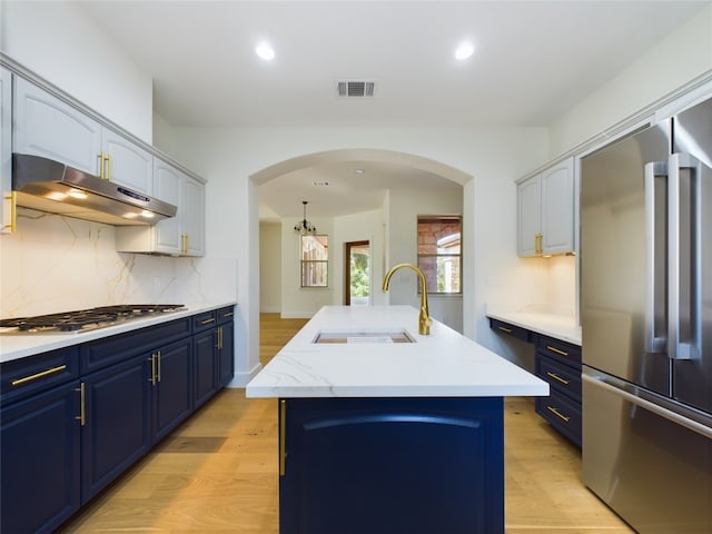 kitchen featuring light hardwood / wood-style flooring, stainless steel appliances, sink, and an island with sink