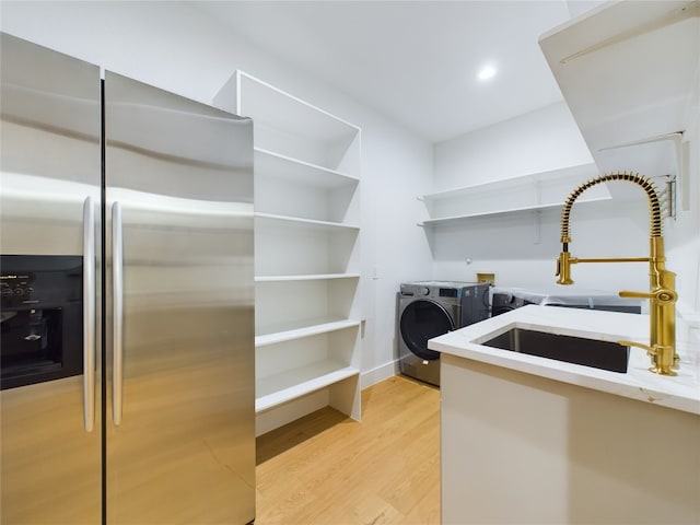 laundry area featuring sink, washing machine and dryer, and light wood-type flooring