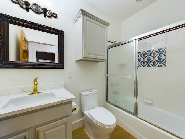 full bathroom with vanity, toilet, bath / shower combo with glass door, and hardwood / wood-style floors