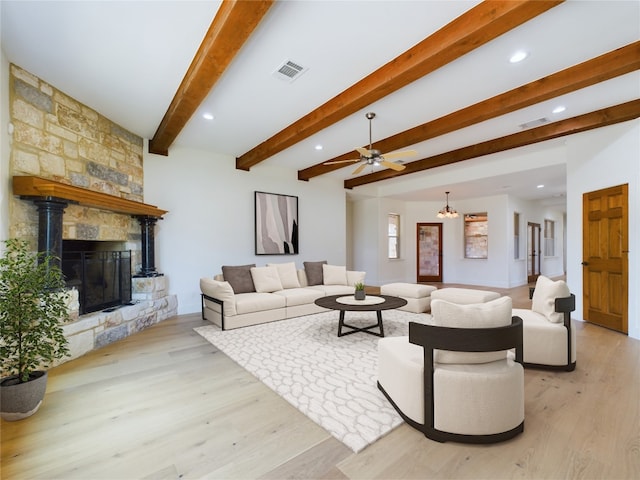 living room featuring beam ceiling, light hardwood / wood-style flooring, a fireplace, and ceiling fan