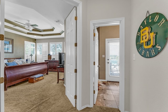 bedroom with a raised ceiling, ceiling fan, light colored carpet, and crown molding