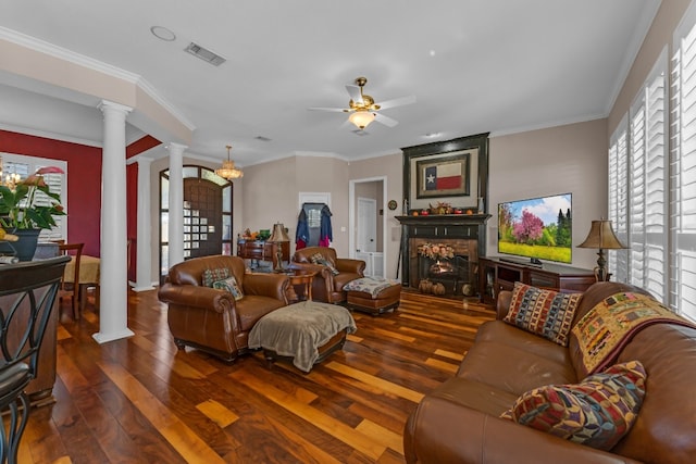 living room with ceiling fan, ornamental molding, a large fireplace, dark hardwood / wood-style flooring, and decorative columns