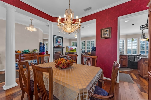 dining space with a chandelier, dark hardwood / wood-style flooring, ornate columns, and ornamental molding