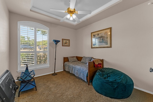 carpeted bedroom with a raised ceiling, ceiling fan, and ornamental molding