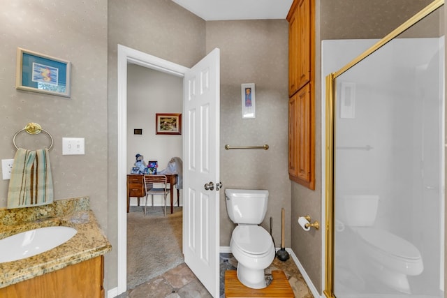 bathroom featuring a shower with door, vanity, and toilet