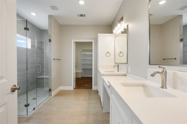 bathroom featuring a shower with door and vanity