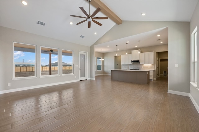 unfurnished living room with hardwood / wood-style flooring, beamed ceiling, high vaulted ceiling, and ceiling fan