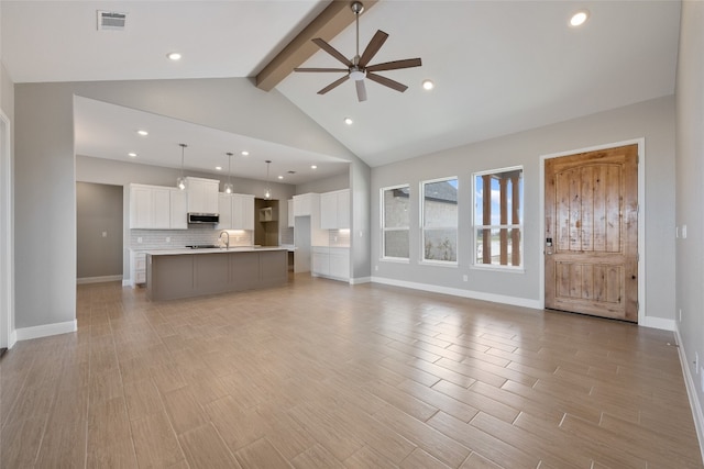 unfurnished living room with sink, light hardwood / wood-style floors, ceiling fan, beam ceiling, and high vaulted ceiling