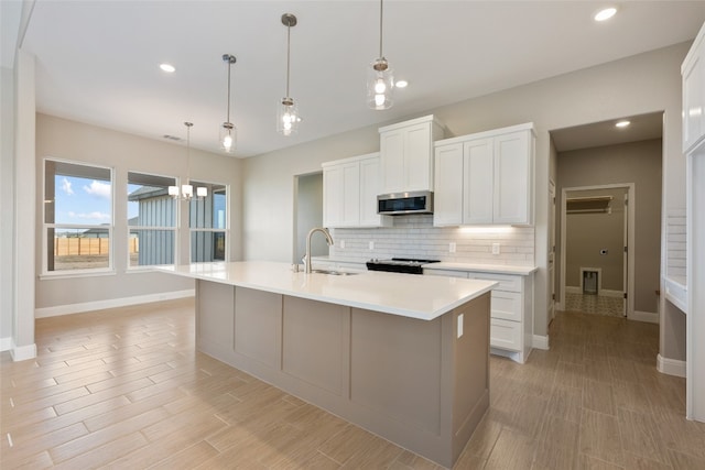 kitchen featuring sink, white cabinetry, and an island with sink