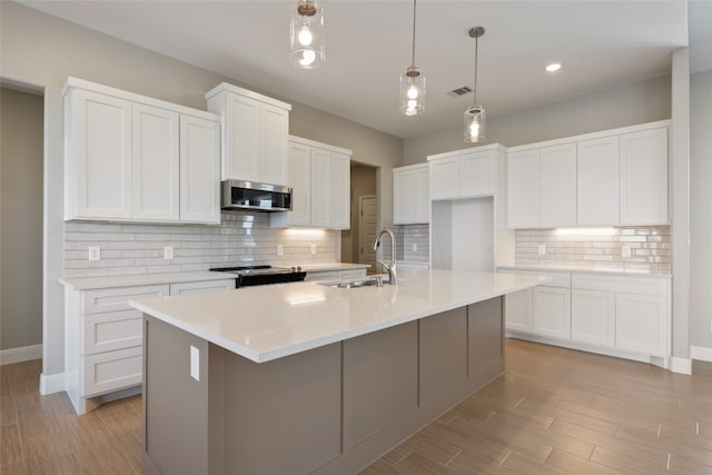 kitchen with white cabinets, backsplash, a kitchen island with sink, sink, and stainless steel appliances