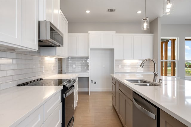 kitchen featuring white cabinetry, hanging light fixtures, stainless steel appliances, and sink