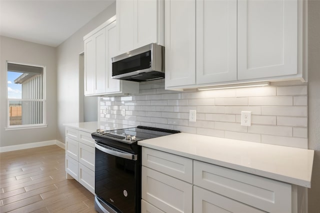 kitchen with range with electric cooktop, white cabinets, light hardwood / wood-style flooring, and backsplash