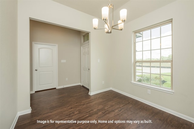 empty room featuring a wealth of natural light, dark hardwood / wood-style floors, and an inviting chandelier