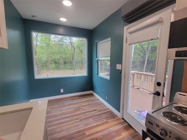 interior space featuring an AC wall unit, light wood-type flooring, and plenty of natural light