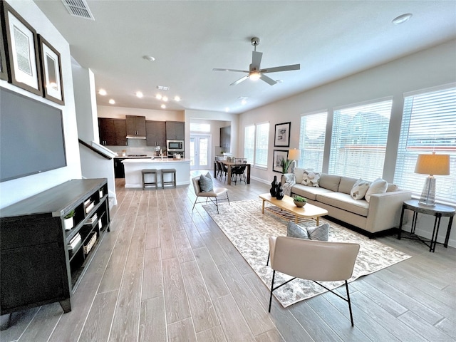 living room with light hardwood / wood-style floors and ceiling fan