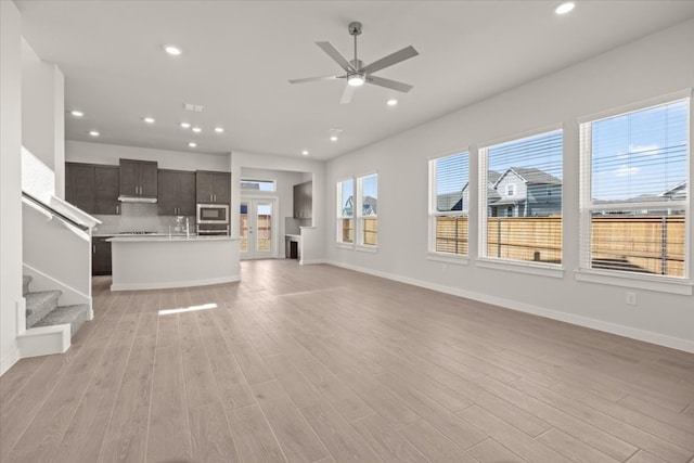 unfurnished living room with light hardwood / wood-style flooring, sink, and ceiling fan