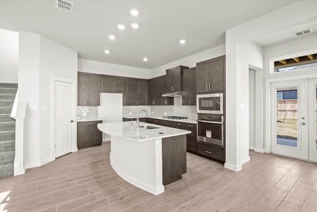 kitchen featuring light hardwood / wood-style flooring, stainless steel appliances, sink, and a center island with sink