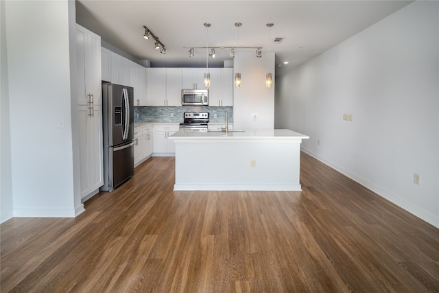 kitchen with appliances with stainless steel finishes, hanging light fixtures, white cabinetry, dark wood-type flooring, and a center island with sink