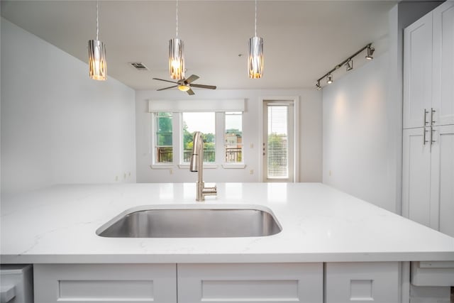 kitchen featuring light stone counters, sink, decorative light fixtures, and white cabinetry