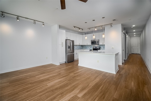 kitchen with white cabinetry, a kitchen island with sink, pendant lighting, light hardwood / wood-style floors, and stainless steel appliances