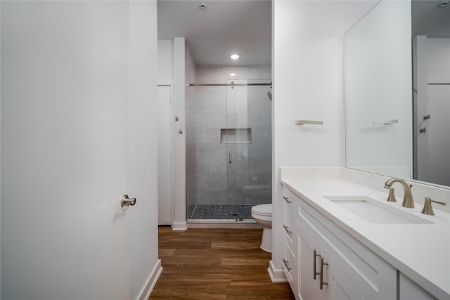 bathroom featuring a shower with door, vanity, wood-type flooring, and toilet