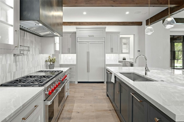 kitchen featuring wall chimney exhaust hood, beamed ceiling, sink, and premium appliances