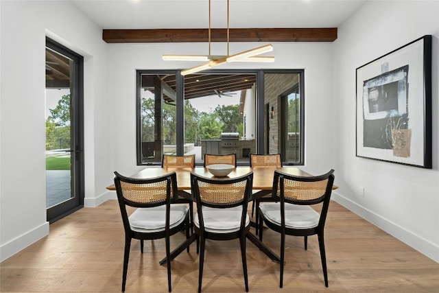 dining area with light hardwood / wood-style flooring, beam ceiling, and a healthy amount of sunlight