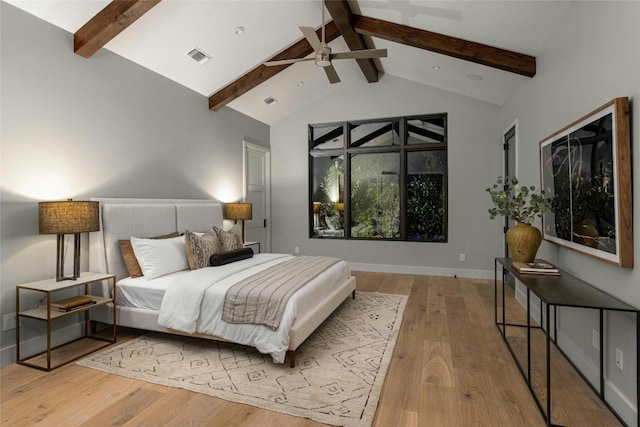 bedroom with ceiling fan, light wood-type flooring, and vaulted ceiling with beams