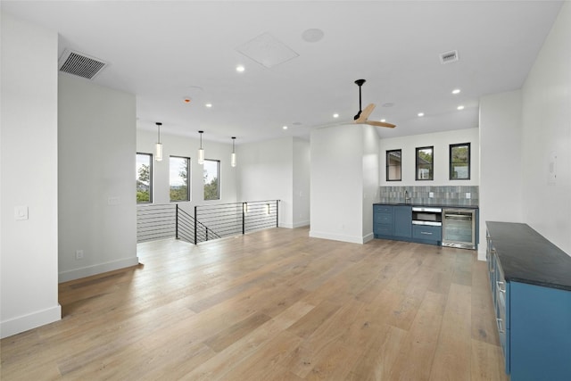 unfurnished living room with beverage cooler, light wood-type flooring, and ceiling fan