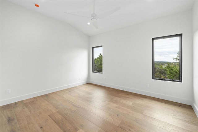 empty room with lofted ceiling, ceiling fan, plenty of natural light, and light wood-type flooring