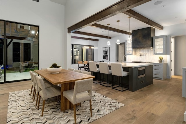 dining room with light hardwood / wood-style flooring and beamed ceiling