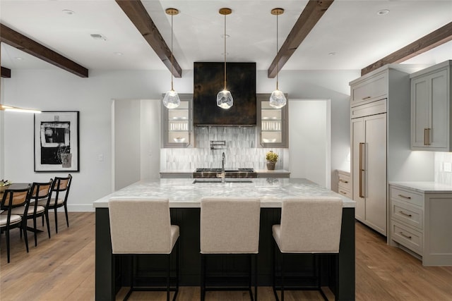 kitchen featuring beamed ceiling, custom exhaust hood, hardwood / wood-style floors, and paneled fridge